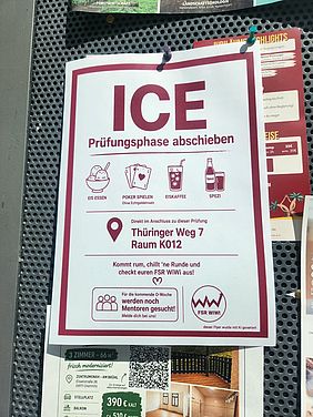 Foto eines hochformatigen weißen Flyers mit dunkelrotem Rahmen. Der Flyer ist mit zwei Reißzwecken an einer schwarzen, gelochten Metallwand befestigt. Hinter und unter ihm sind Ausschnitte weiterer Aushänge zu sehen.  Oben auf dem Flyer steht in sehr großer dunkelroter Schrift „ICE“. Direkt darunter steht „Prüfungsphase abschieben“.  In der nächsten Reihe befinden sich vier dunkelrote Zeichnungen mit Beschriftungen. Von links nach rechts sind zu sehen: eine Schale mit Eiskugeln und der Text „EIS ESSEN“; mehrere Spielkarten und der Text „POKER SPIELEN“, darunter in kleinerer Schrift „Ohne Echtgeld­einsatz“; ein Getränkebecher mit Deckel und Strohhalm und der Text „EISKAFFEE“; sowie eine Flasche neben einem Glas und der Text „SPEZI“.  Darunter befindet sich links ein großes Standort-Symbol. Daneben steht: „Direkt im Anschluss zu dieser Prüfung“. In einem dunkelroten, abgerundeten Feld darunter steht „Thüringer Weg 7, Raum K012“.  Im unteren Bereich des Flyers steht: „Kommt rum, chillt ’ne Runde und checkt euren FSR WiWi aus!“ Darunter ist ein kleines Herz abgebildet.  Links unten befindet sich ein abgerundeter Kasten mit einem Symbol aus drei Personen. Darin steht: „Für die kommende O-Woche werden noch Mentoren gesucht! Melde dich bei uns!“ Rechts daneben ist ein rundes Logo mit der Aufschrift „FSR WiWi“ und einer roten Zickzacklinie zu sehen. Ganz unten rechts steht in kleiner Schrift: „dieser Flyer wurde mit KI generiert“.