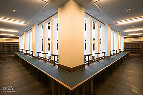 Ein Foto aus der Ecke eines Raumes. Zwei durchgehende Tische lassen den Raum wie zwei Gänge erscheinen. 