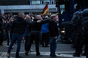 Teilnehmer der rassistischen Ausschreitungen vor einem Jahr attakieren eine Polizeikette